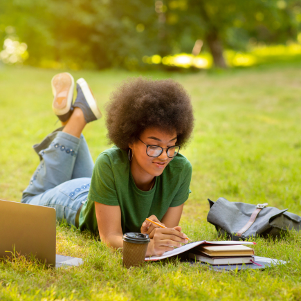 High school student doing homework for online school in the park on a late summer afternoon.