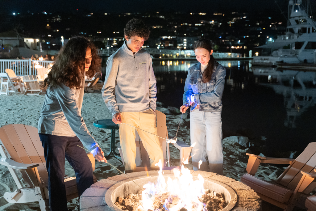 Students enjoying a beach bonfire making s'mores during YEC 2025